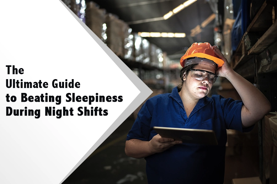 Tired night shift warehouse worker wearing a safety helmet and using a tablet, with tips and strategies to beat sleepiness during night shifts
