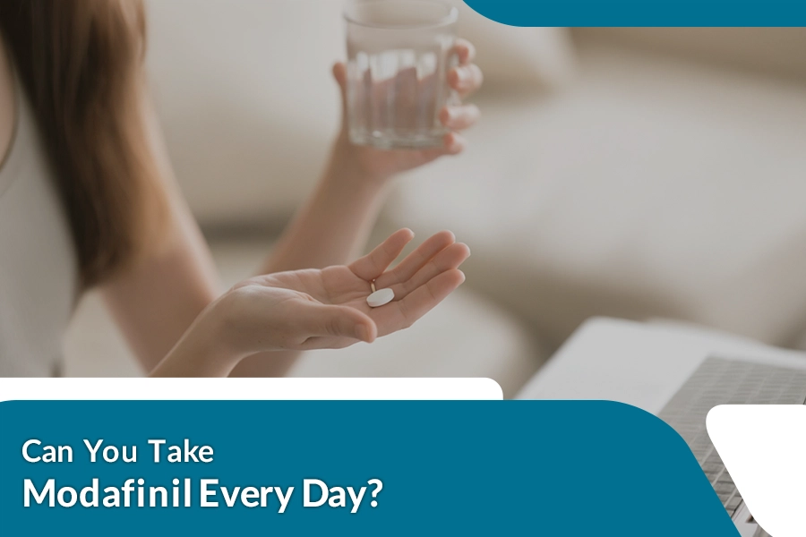 Person holding a tablet with water while considering daily use of Modafinil